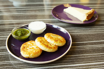 Homemade Salty Cheese Pancakes with sauce Pesto. Cheesecake dessert on the background. Pancakes photographed close.