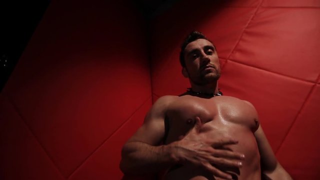 Brutal muscular man in the red room dancing. stripper handcuffed