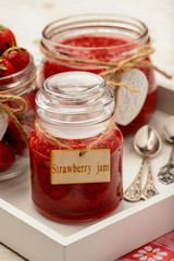 Fototapeta na wymiar Strawberry jam in glass jars on wooden background.