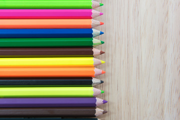 Colors pencils, colorful many crayons on wood background