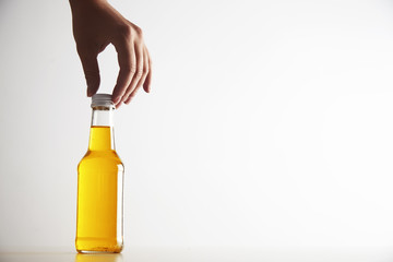 Woman hand takes carefully bottle with yellow drink inside for long neck, unlabeled, isolated on...