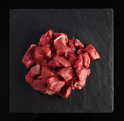 Pieces of raw fresh meat isolated on black on stone board, top view