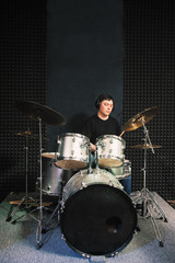 Drummer in headphones playing solo on drum set. Front view on male drummer playing sound...