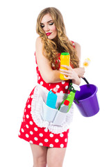 Obraz premium Blonde girl in a red dress housewife with curlers in the house cleaning. Housekeeper with cleaning tools: a bucket, a mop, detergents, isolated on white background.