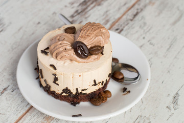 
 Round cake on a dessert plate.     Round cake on a white dessert plate on a light wooden background.