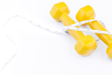 Fitness equipment . Yellow dumbbell with measuring tape on white