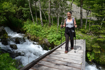 Randonneuse sur un pont traversant la rivière du Prentiq  dans le parc national des Écrins 