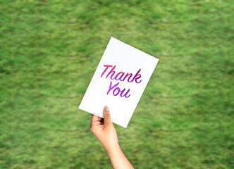 Thank you on card hand holding with blurred grass background