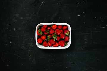 Fresh strawberry in the white basket on the black table