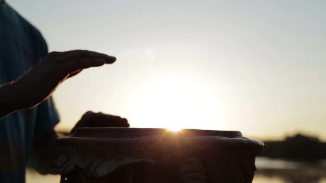 игра на джембе или атабаке на фоне природы во время заката