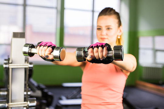 fitness, sport, training and lifestyle concept - happy woman with dumbbells flexing muscles in gym