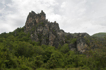 Fototapeta na wymiar Eroded rocks in mountains against gray cloudy sky background