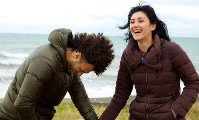 Happy couple in love laughing holding hand in front of ocean