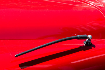 Close up of a folded antenna on a red classic car