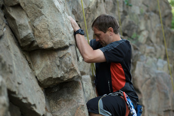 Obraz na płótnie Canvas Male rock climber clings to a cliff
