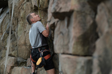 Male rock climber clings to a cliff