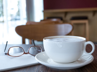 Open a blank white notebook with hot coffee on table