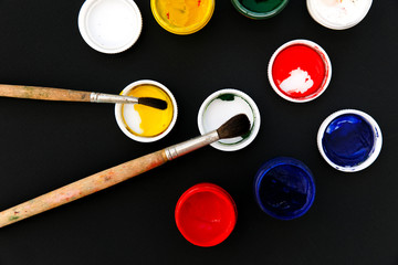 Gouache colors and paint brushes on black background
