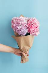 Woman hand holding flowers over blue background