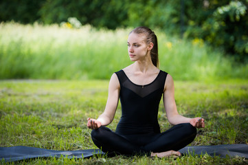 Beautiful young girl meditating in summer park