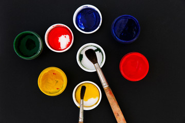 Gouache colors and paint brushes on black background