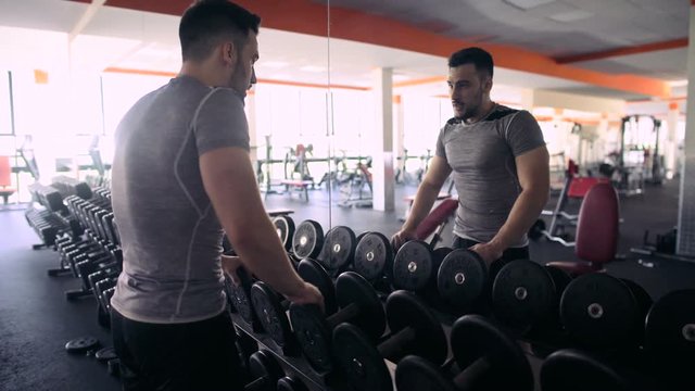 Young Male Athlete Is Resting Near The Mirror In The Gym