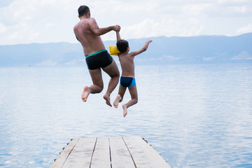 Father and son jumping into lake