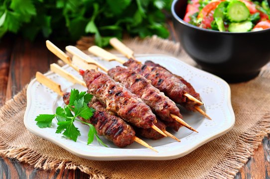 Homemade kebabs on skewers with a salad of tomato and cucumber.