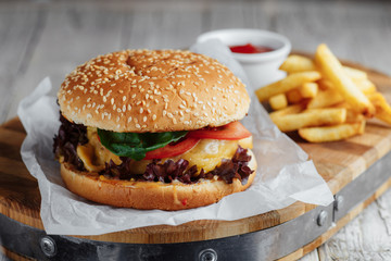 Hamburger, french fries and ketchup on a wooden tray on a wooden table