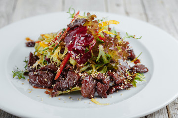 Salad with beef in a sweet sauce on a white plate