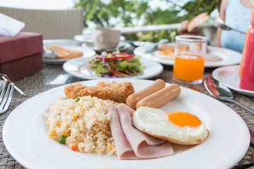 Breakfast with fired rice, fried egg, ham, sausage, fired fish,