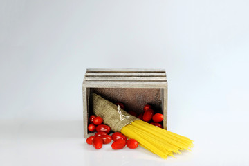 Spaghetti and tomatoes in wooden box