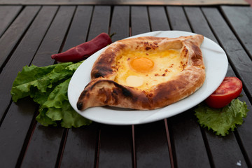 Adjarian khachapuri with eggs on wooden table