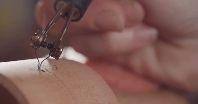 Artist using pyrography to decorate a Buddhist prayer wheel