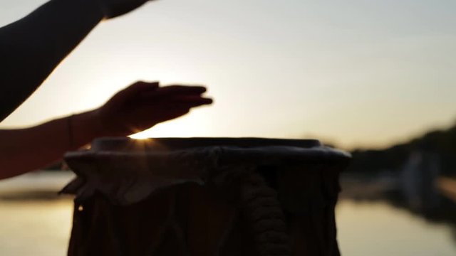 игра на джембе или атабаке на фоне природы во время заката