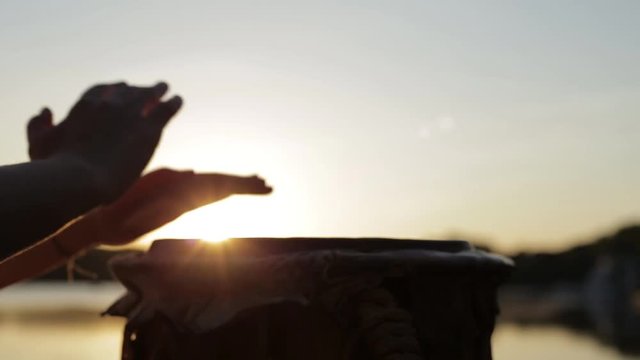 игра на джембе или атабаке на фоне природы во время заката