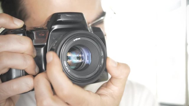 Photographer takes pictures with DSLR pro camera. You can see the aperture blades closing.