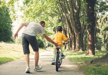 Obraz premium Father learn his little son to ride a bicycle