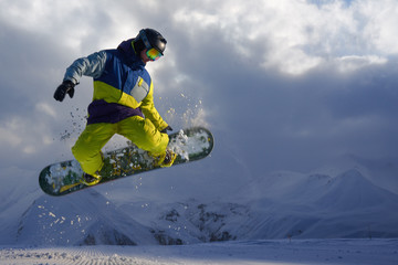 snowboarder does the jumping trick. snow scatters pieces