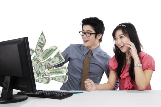 Happy businesspeople look money on monitor