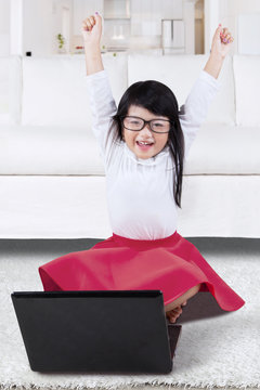Happy girl raise hands with laptop at home