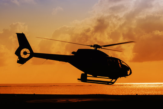 silhouette of helicopter taking off at sunset