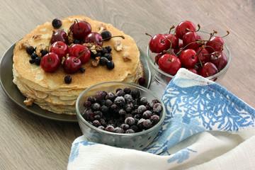 Homemade delicious pancakes. Closeup of pancakes with fresh blueberry and nuts on wooden background. Stack of  pancakes with nuts and maple syrup on plate and napkin. Selective focus