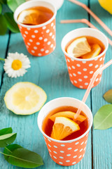 Cold tea with lemon in bright orange paper cups.