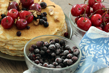 Homemade delicious pancakes. Closeup of pancakes with fresh blueberry and nuts on wooden background. Stack of  pancakes with nuts and maple syrup on plate and napkin. Selective focus