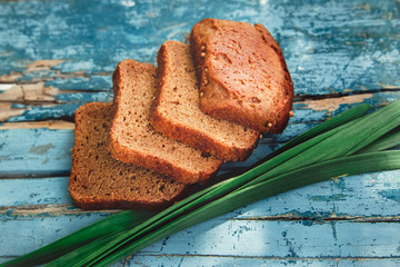 There are Homemade Bread  with Green Fresh Leaves of Garlic on the Vintage Old Painted Wooden Boards,Rural Natural Food,Baking,Top View