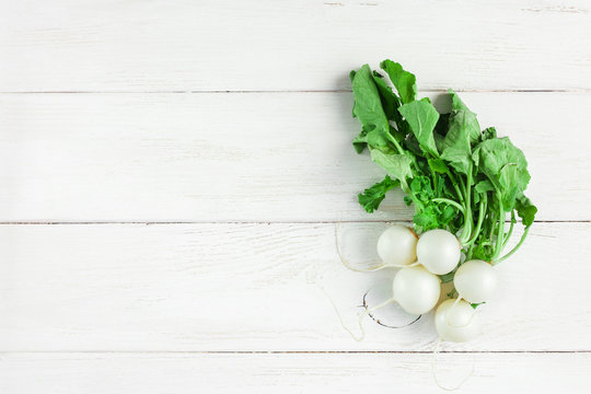 white radishes on a white wooden background, flat lay, top view