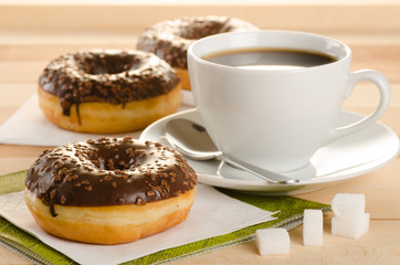 Chocolate donuts with coffee and sugar on the wooden table
