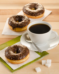 Chocolate donuts with coffee and sugar on the wooden table