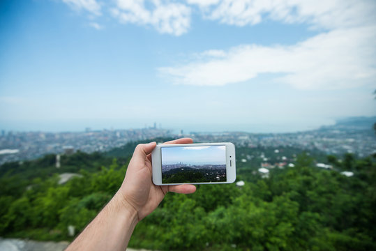 Hand with smartphone taken pictures of city landscape